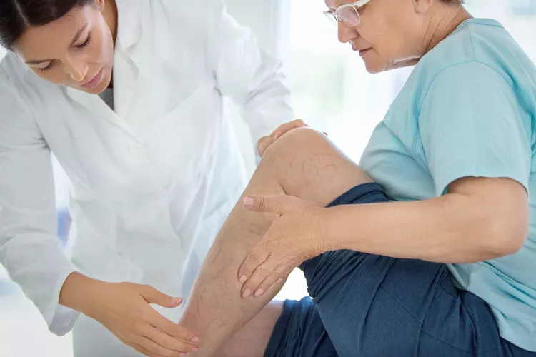 A high-definition image of an elderly person receiving a vein health check-up from a healthcare professional in a clinical setting.