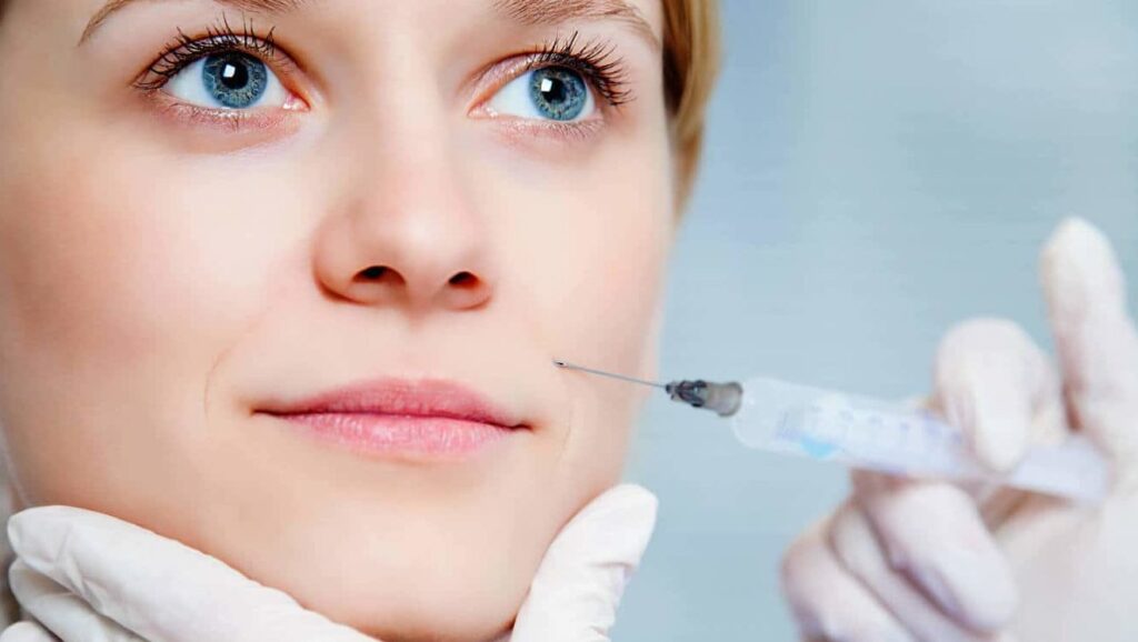 A professional administering a Botox injection to a smiling patient in a clinical setting.
